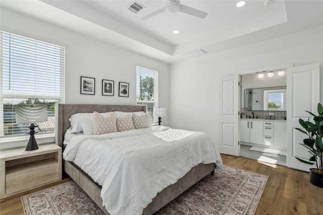 bedroom with hardwood / wood-style floors, ceiling fan, a raised ceiling, and sink