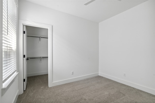 unfurnished bedroom featuring ceiling fan, a closet, light carpet, and multiple windows