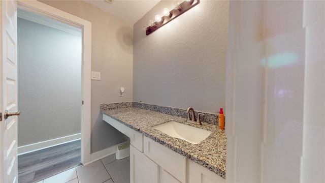 bathroom with a textured wall, tile patterned flooring, baseboards, and vanity