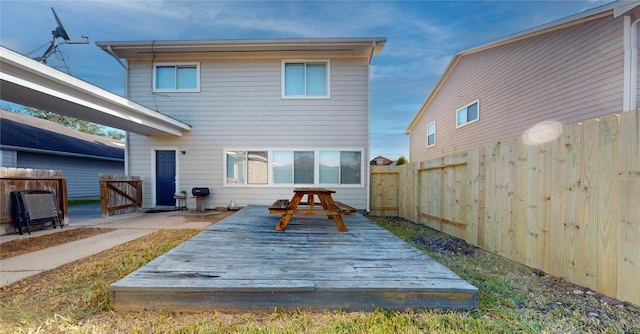 rear view of house featuring fence and a wooden deck