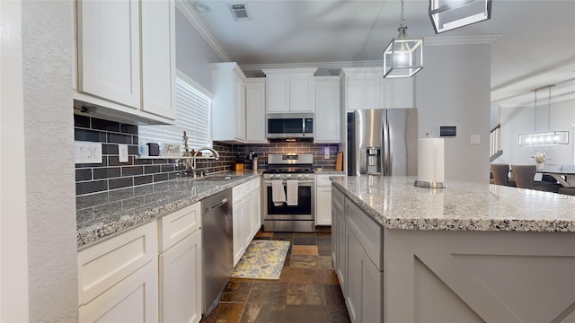 kitchen with decorative light fixtures, appliances with stainless steel finishes, white cabinets, a kitchen island, and a sink