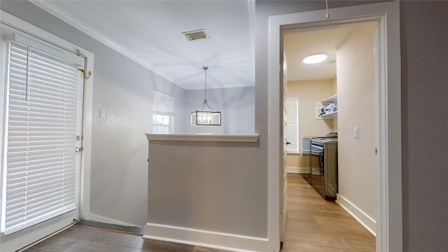 foyer with crown molding, baseboards, visible vents, and light wood-style floors