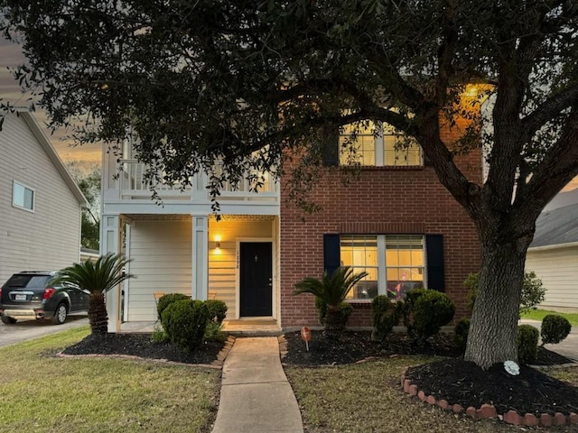 view of front of house featuring a balcony and a yard