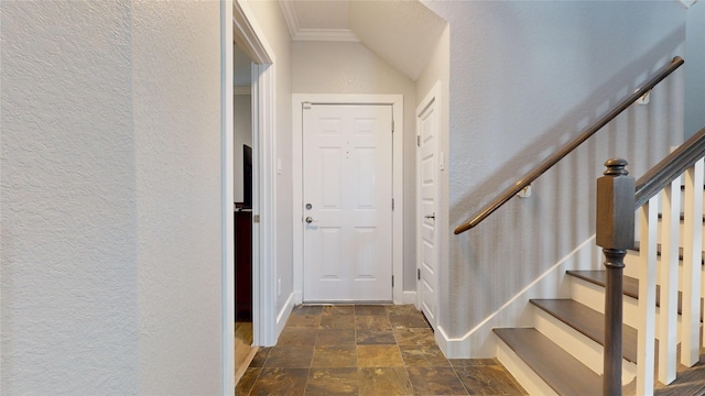 foyer entrance with ornamental molding, stone finish flooring, a textured wall, and stairway