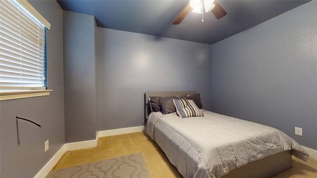 bedroom featuring a ceiling fan, light carpet, and baseboards