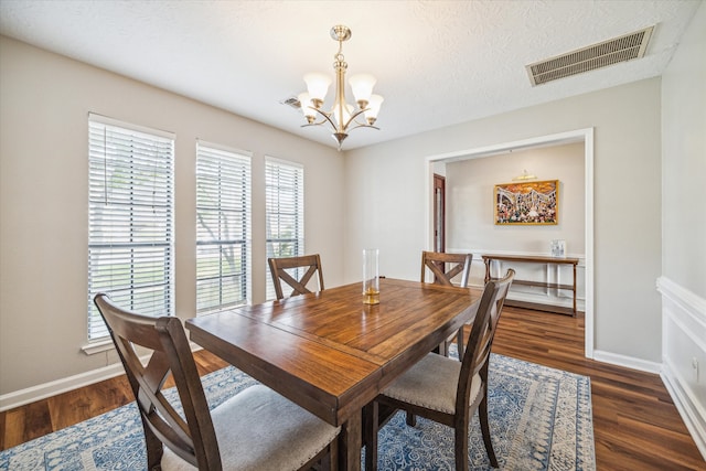 dining space featuring dark wood-type flooring, a chandelier, and a textured ceiling