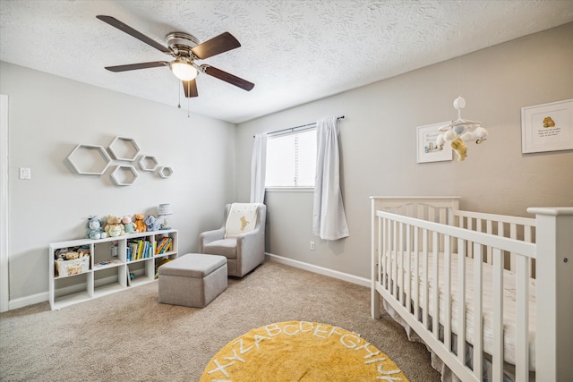 carpeted bedroom with ceiling fan, a textured ceiling, and a crib