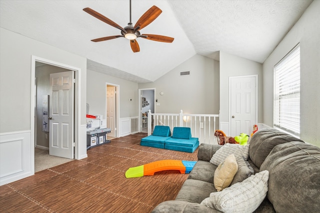 carpeted living room featuring ceiling fan, vaulted ceiling, and a textured ceiling