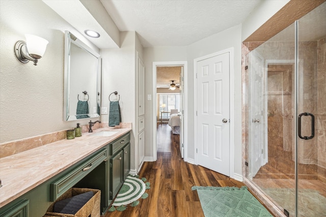 bathroom featuring vanity, a shower with shower door, hardwood / wood-style floors, and a textured ceiling