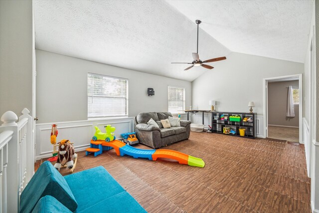 game room featuring lofted ceiling, ceiling fan, and a textured ceiling