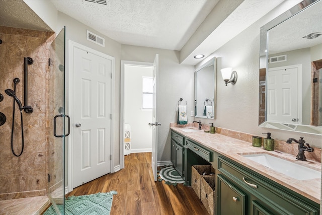 bathroom featuring hardwood / wood-style flooring, vanity, an enclosed shower, and a textured ceiling