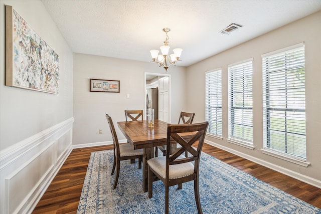 dining area featuring an inviting chandelier, dark wood-type flooring, and a textured ceiling