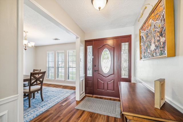 entrance foyer with an inviting chandelier, dark hardwood / wood-style floors, and a textured ceiling