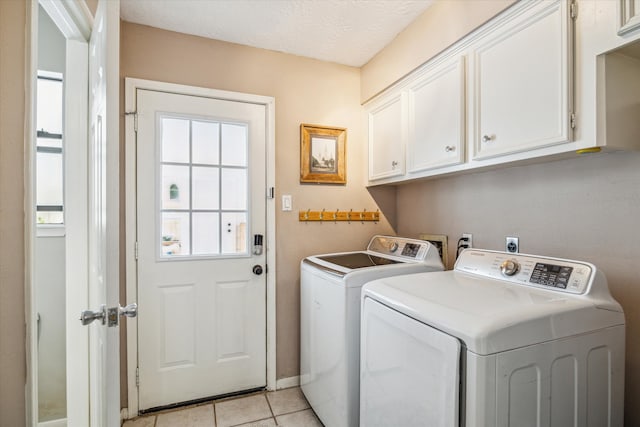 laundry area featuring cabinets, light tile patterned floors, a textured ceiling, and washer and clothes dryer