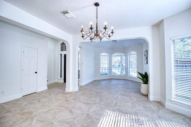 interior space featuring plenty of natural light, an inviting chandelier, and light parquet flooring