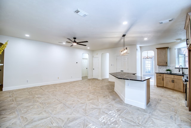 kitchen with ceiling fan, sink, a center island, hanging light fixtures, and light parquet floors