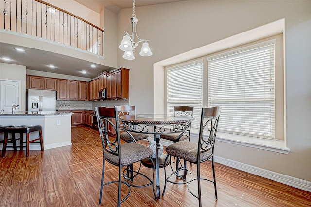 dining room with light hardwood / wood-style flooring, a high ceiling, and a notable chandelier