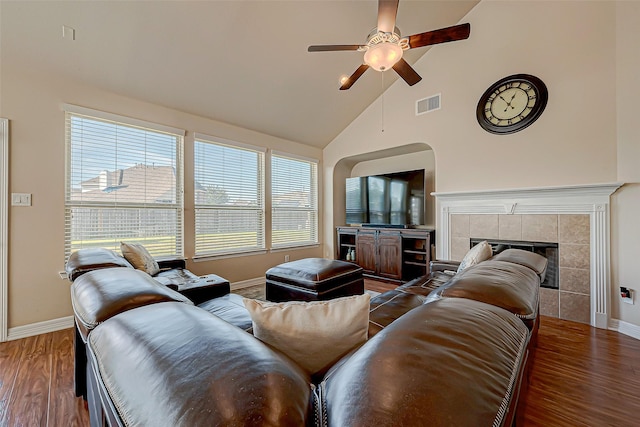 living room featuring wood-type flooring, ceiling fan, lofted ceiling, and a tiled fireplace