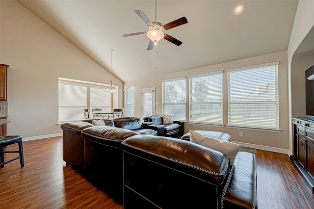 living room with ceiling fan with notable chandelier, dark hardwood / wood-style flooring, and high vaulted ceiling