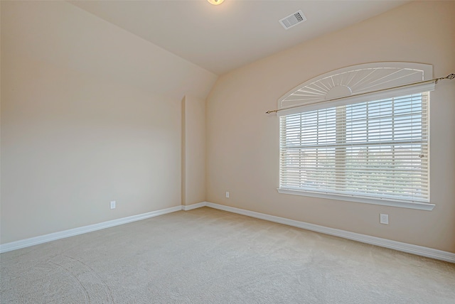 unfurnished room featuring light colored carpet and vaulted ceiling