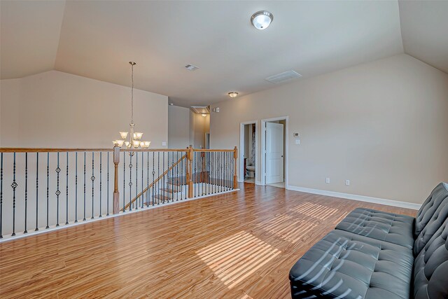 unfurnished room with an inviting chandelier, vaulted ceiling, and hardwood / wood-style flooring