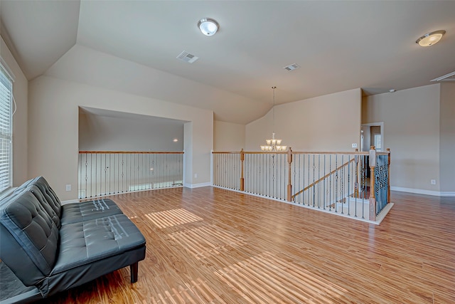 sitting room featuring hardwood / wood-style floors, a chandelier, and vaulted ceiling