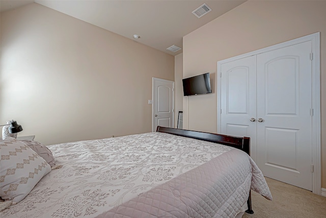 bedroom with light colored carpet, vaulted ceiling, and a closet