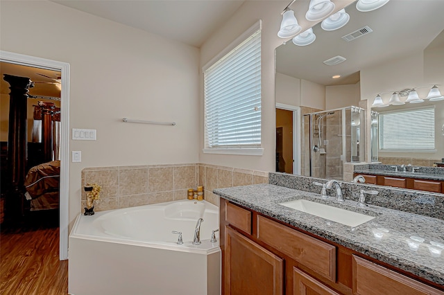 bathroom featuring hardwood / wood-style floors, vanity, and plus walk in shower