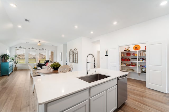 kitchen with ceiling fan, sink, stainless steel dishwasher, an island with sink, and light wood-type flooring