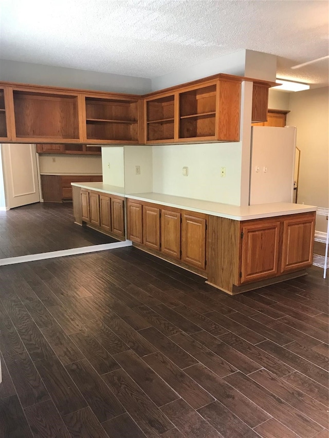 kitchen featuring a textured ceiling, white refrigerator, and dark wood-type flooring