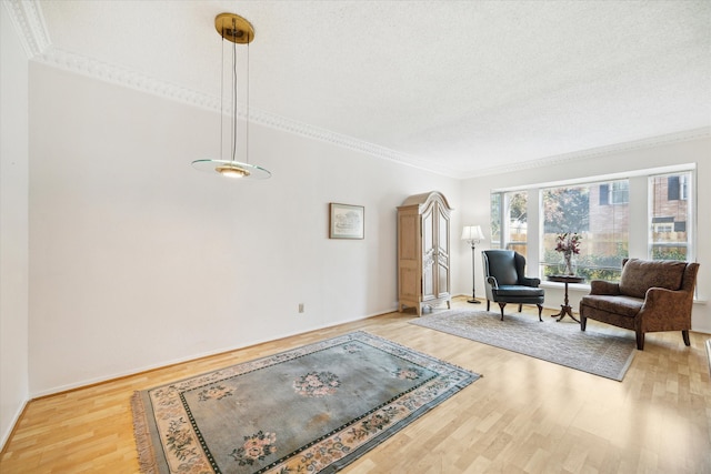 living area with crown molding, light hardwood / wood-style flooring, and a textured ceiling