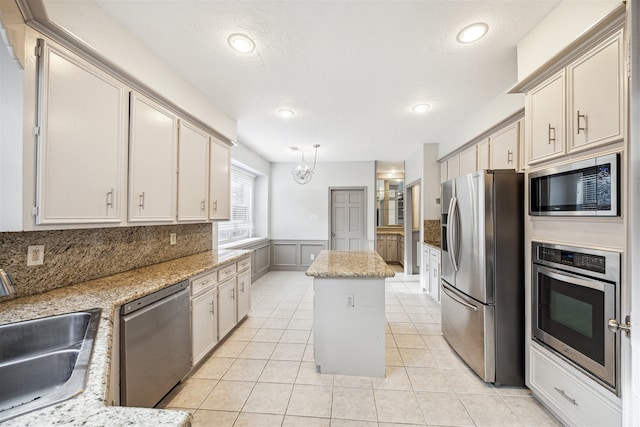 kitchen featuring a kitchen island, light stone countertops, sink, and appliances with stainless steel finishes