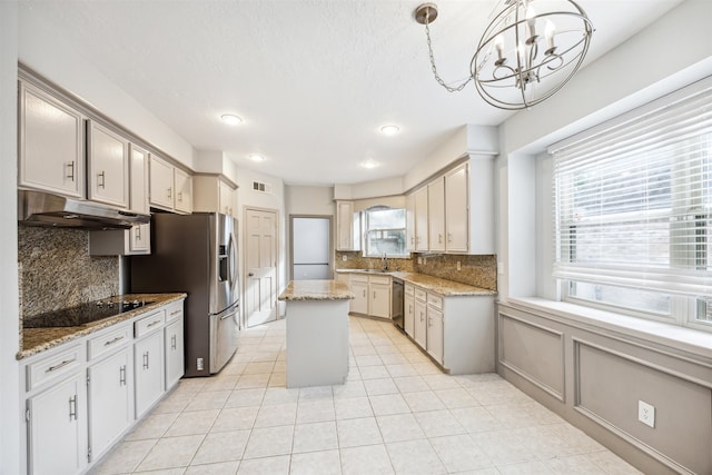 kitchen featuring plenty of natural light, a kitchen island, stainless steel appliances, and an inviting chandelier