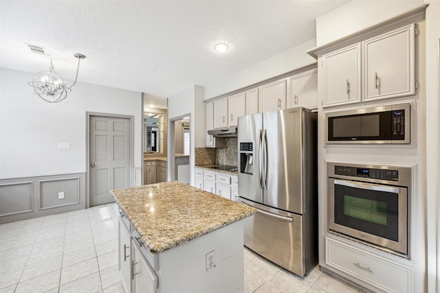 kitchen with appliances with stainless steel finishes, a textured ceiling, an inviting chandelier, and a kitchen island