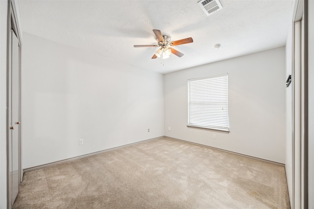 unfurnished bedroom featuring light carpet, a textured ceiling, and ceiling fan