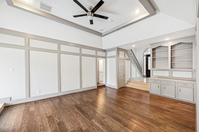 unfurnished living room featuring a tray ceiling, ceiling fan, dark hardwood / wood-style flooring, and a high ceiling