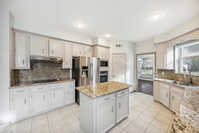 kitchen with a center island, exhaust hood, sink, light stone countertops, and appliances with stainless steel finishes