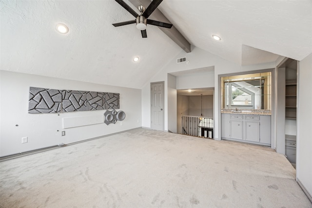 unfurnished living room with carpet flooring, ceiling fan, lofted ceiling with beams, and a textured ceiling