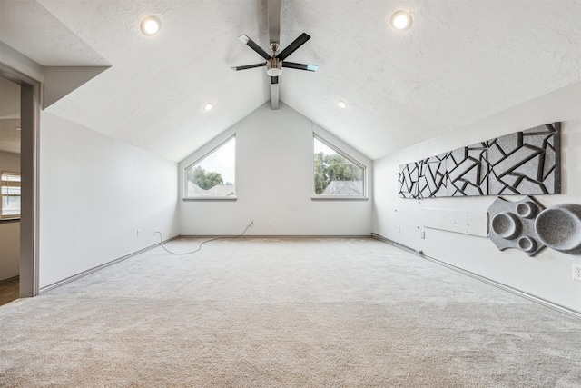 additional living space featuring carpet flooring, a textured ceiling, vaulted ceiling, and ceiling fan