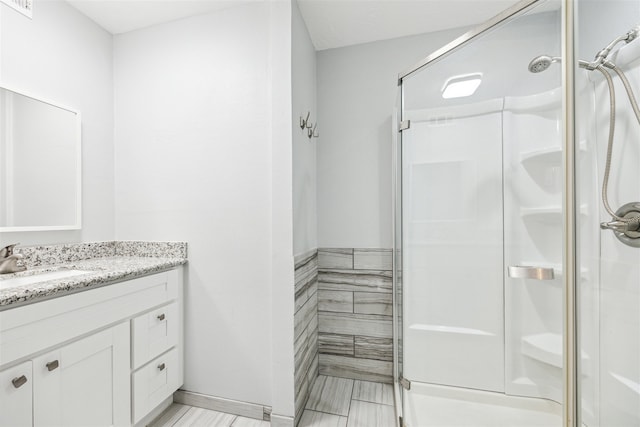 bathroom with tile patterned flooring, vanity, and walk in shower