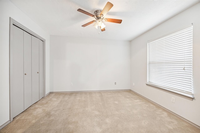 unfurnished bedroom with ceiling fan, light carpet, and a closet