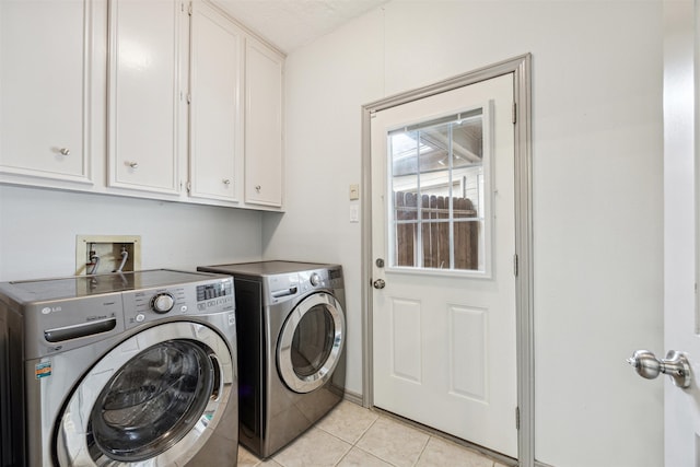 laundry area with light tile patterned flooring, cabinets, and independent washer and dryer