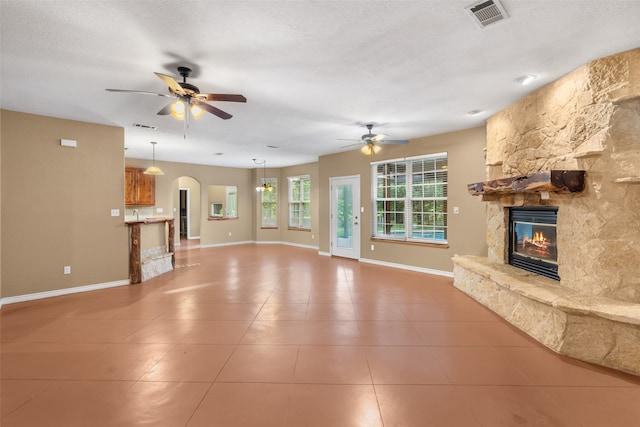 unfurnished living room featuring a textured ceiling, ceiling fan, and a fireplace