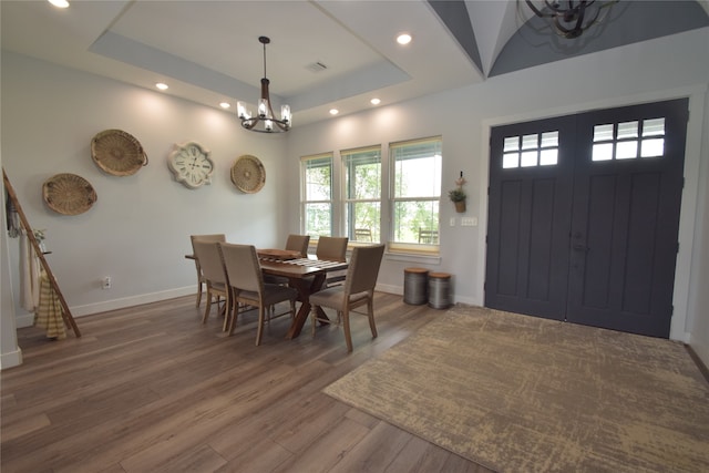 dining room with a tray ceiling, hardwood / wood-style floors, and a chandelier