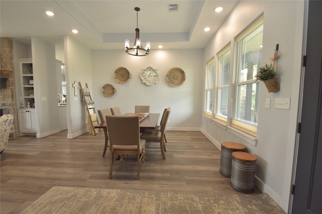 dining room featuring a fireplace, dark hardwood / wood-style floors, an inviting chandelier, and a tray ceiling