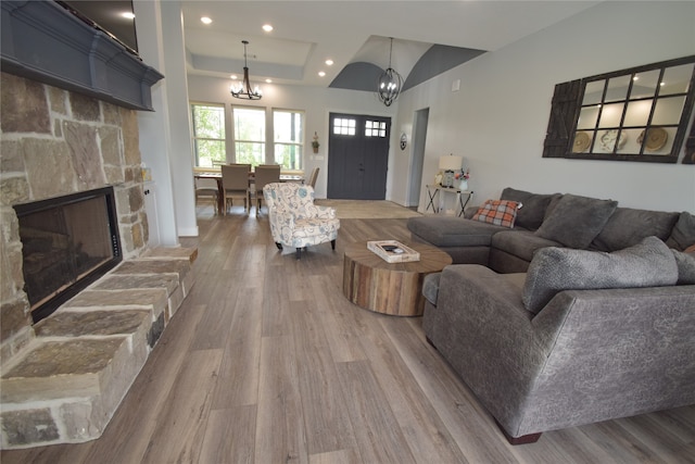 living room featuring a raised ceiling, a notable chandelier, lofted ceiling, a fireplace, and hardwood / wood-style flooring