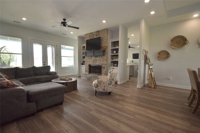 living room featuring a fireplace, hardwood / wood-style floors, french doors, and ceiling fan