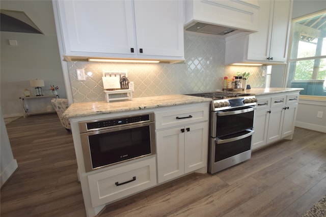 kitchen featuring white cabinets, stainless steel appliances, premium range hood, and light hardwood / wood-style floors