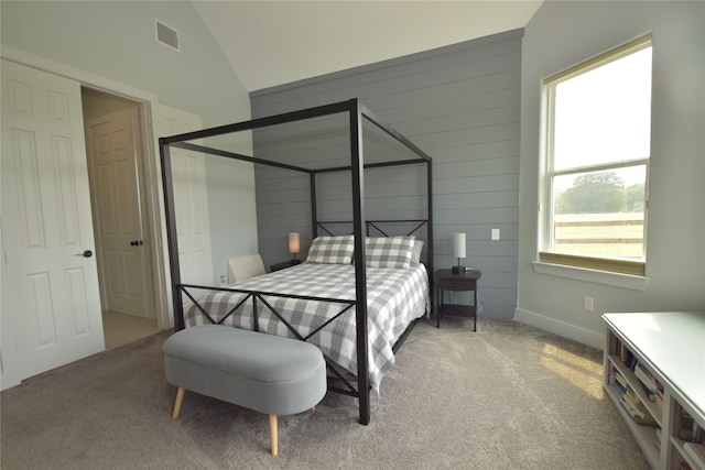 carpeted bedroom featuring wooden walls and lofted ceiling