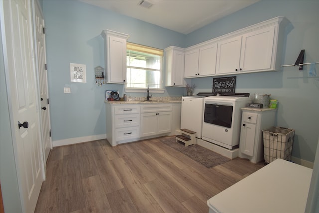 laundry area with cabinets, sink, light hardwood / wood-style floors, and independent washer and dryer